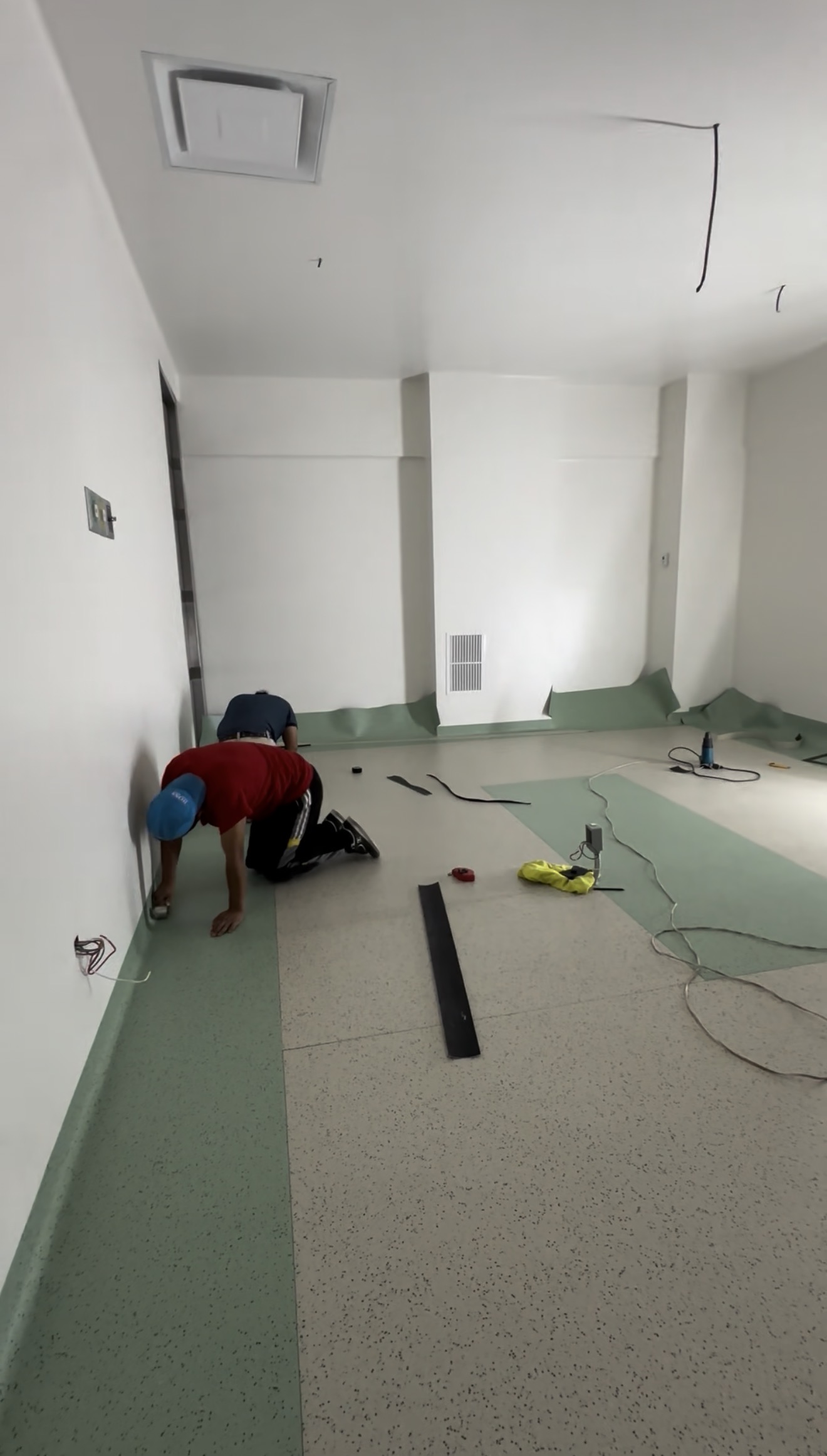Técnicos instalando curva sanitaria en piso vinílico